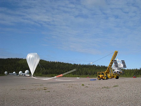 Before launch, the length of the flight train lies on the ground between the spool vehicle (left) and the launch vehicle (right). The checkered part of the train is the re-entry parachute.  Photo: NASA