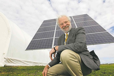 Barry Prentice crouches next to a new solar-power system installed at the BASI hangar, which currently provides heat and light for the operation.  Photo: Ruth Bonneville - Winnipeg Free Press